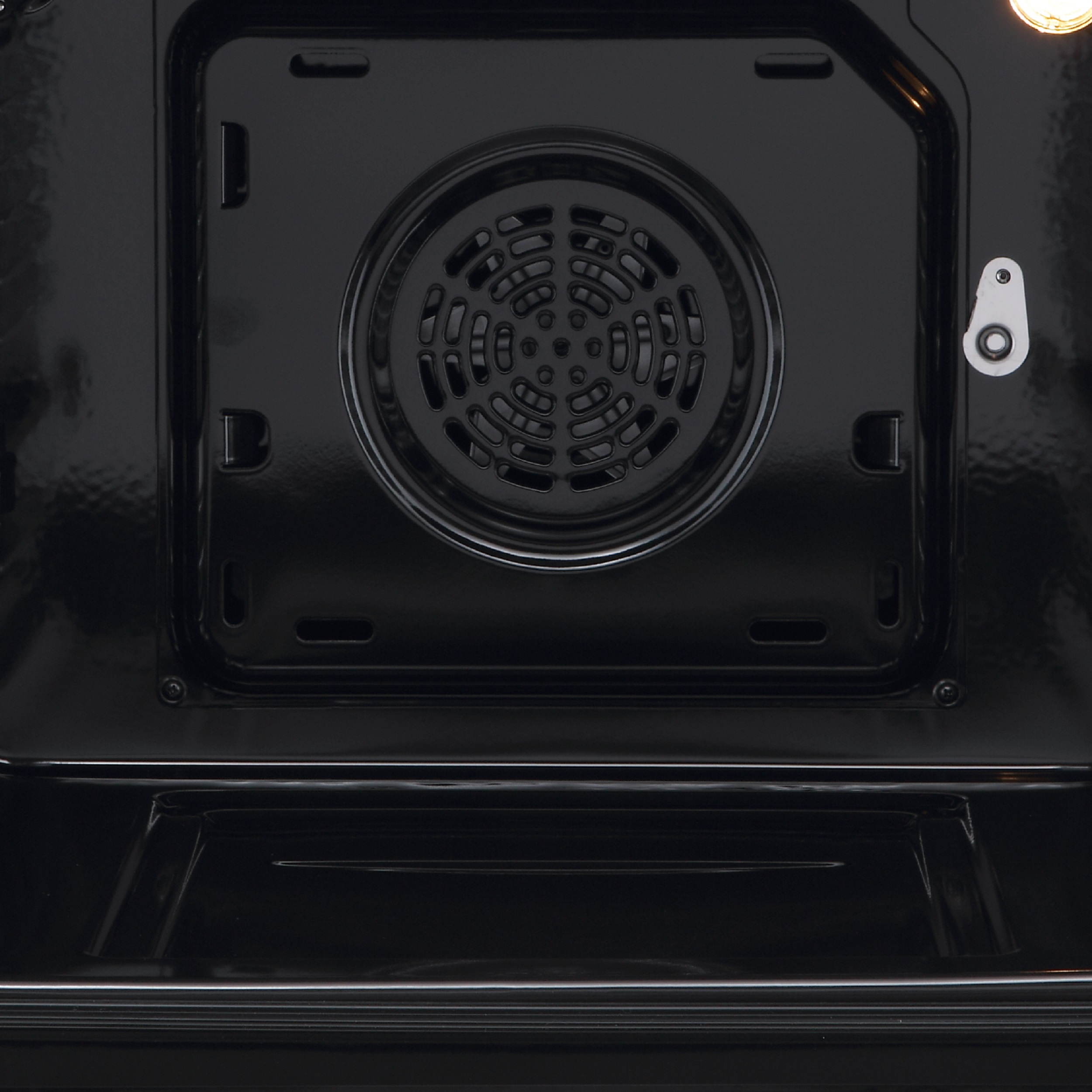 Vista interior de un horno negro con rejilla de ventilador y luz.