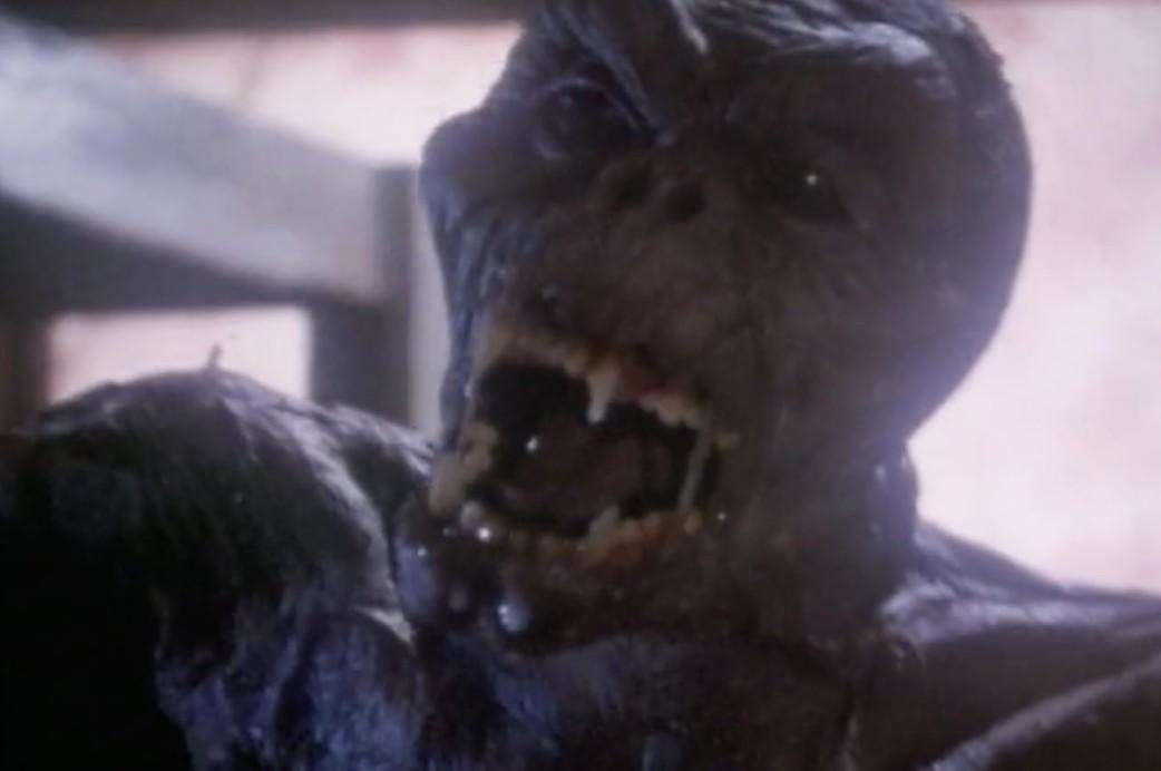Ein dunkles, schleimiges Monster mit offenem Mund und sichtbaren Zähnen.