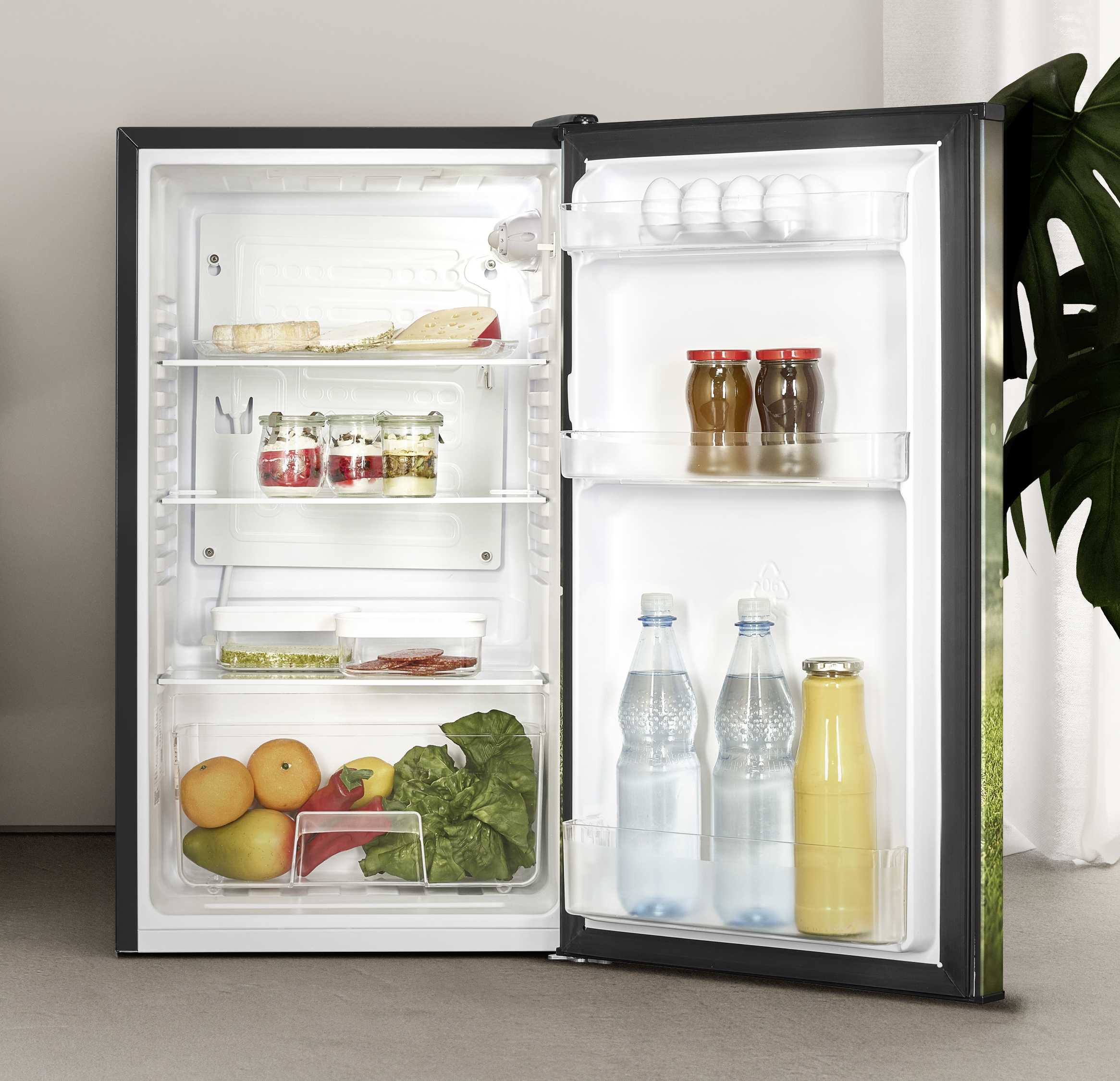 Offener Kühlschrank mit Lebensmitteln: Käse, Gläser, Eier, Flaschen und Obst.