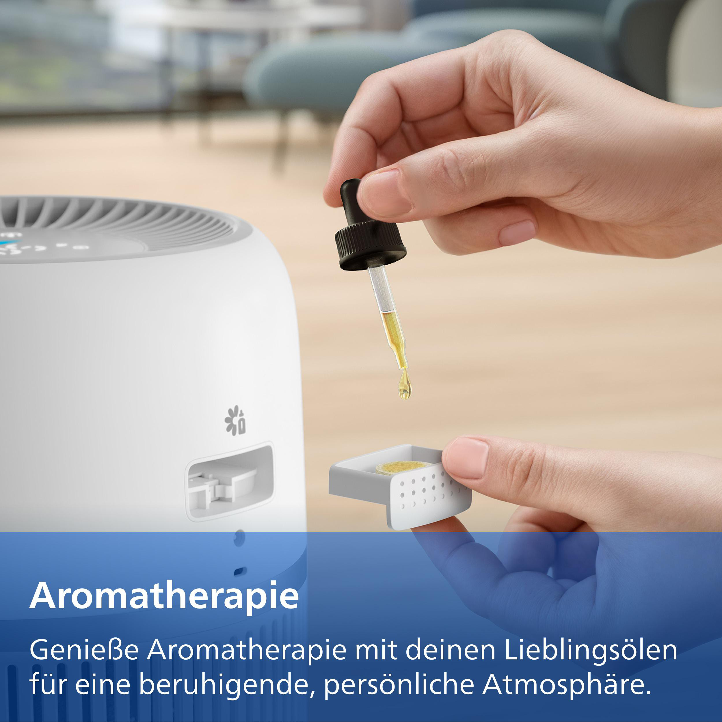 Eine Hand gibt Öltröpfchen in einen kleinen Behälter neben einem Diffusor.