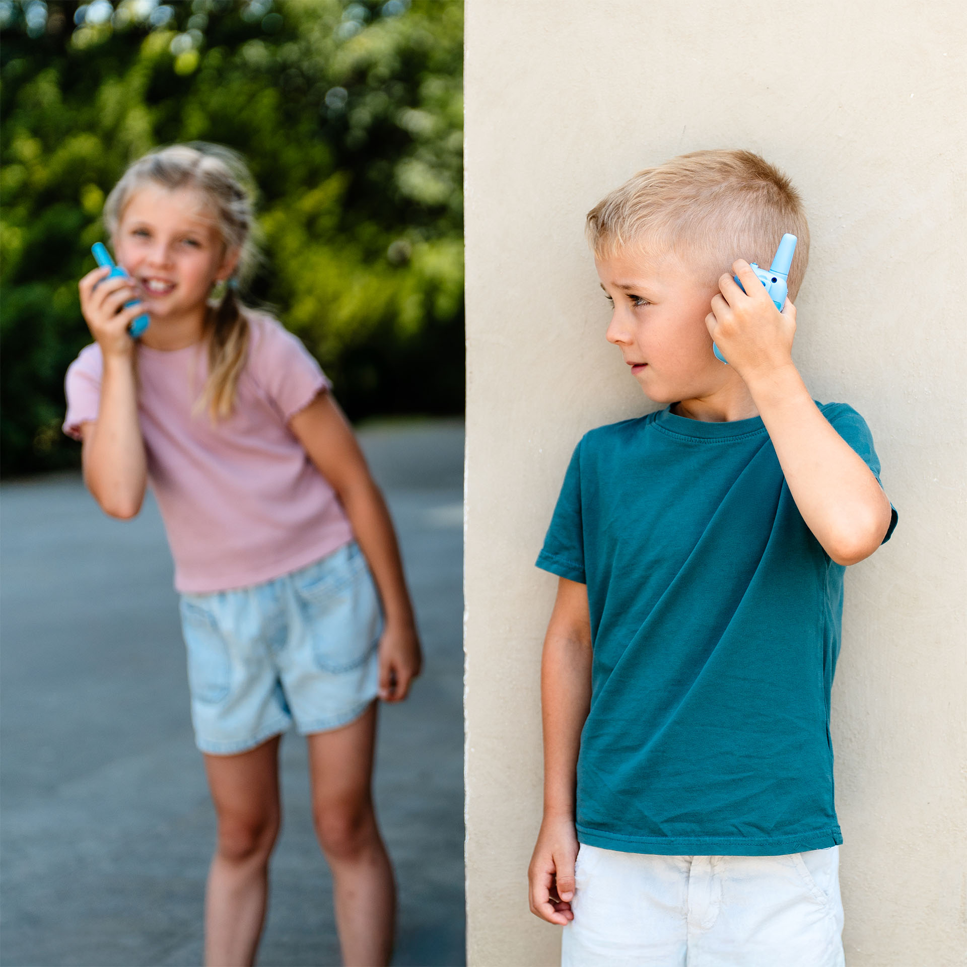 Két gyerek walkie-talkie-t tart. Egy fiú és egy lány beszél bele.