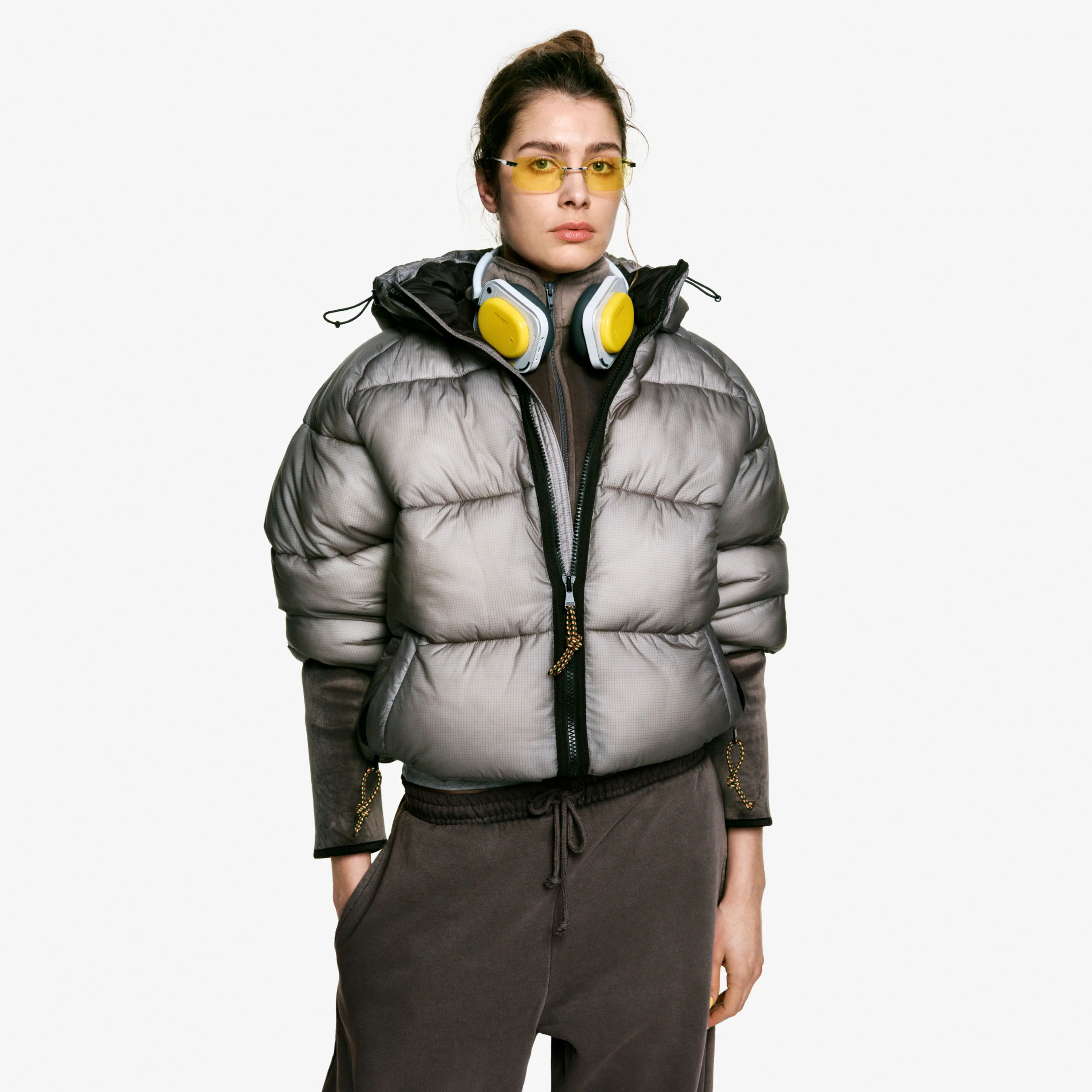 Une femme portant des lunettes jaunes et un casque, vêtue d'une doudoune grise.