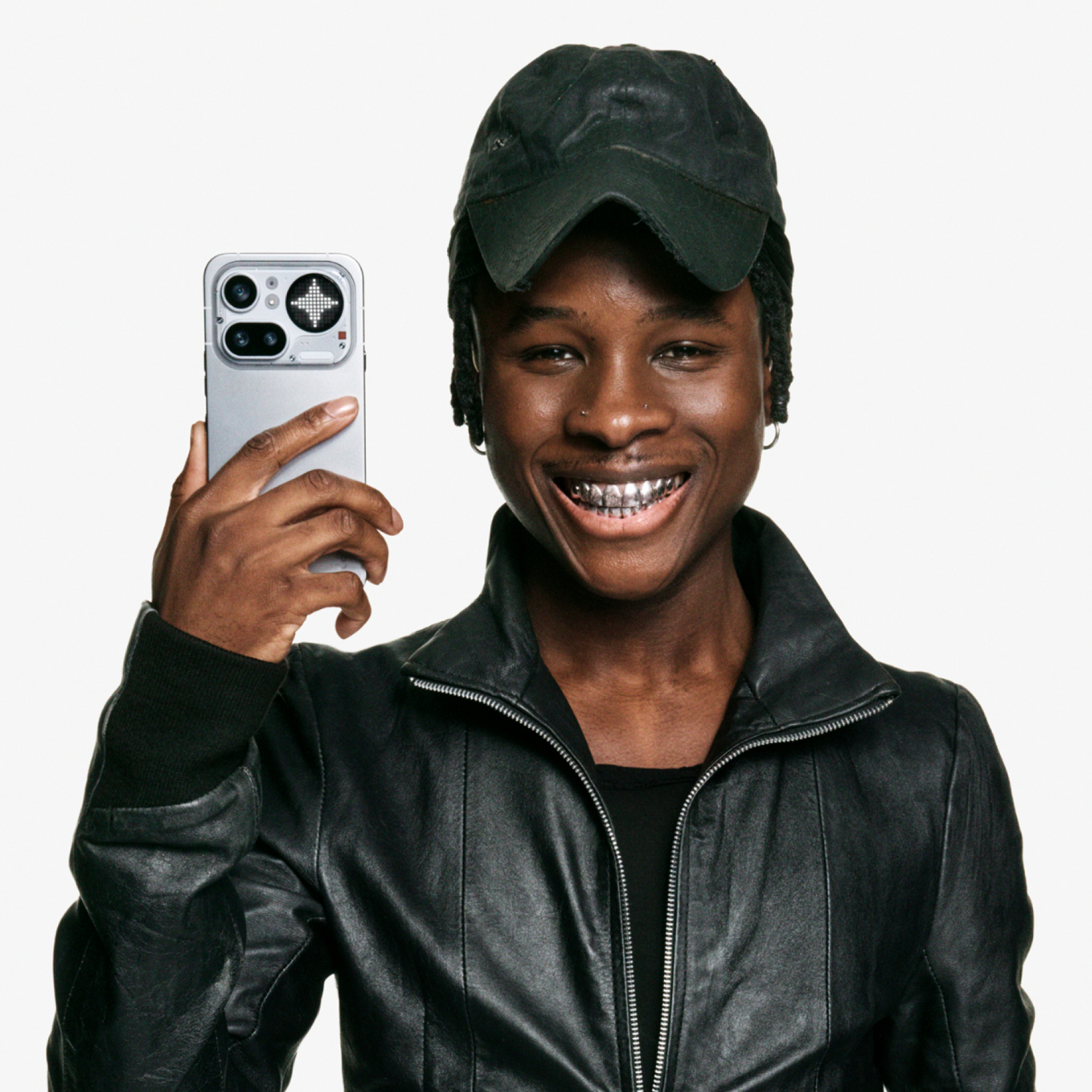 Un uomo con cappellino nero e giacca di pelle tiene uno smartphone.