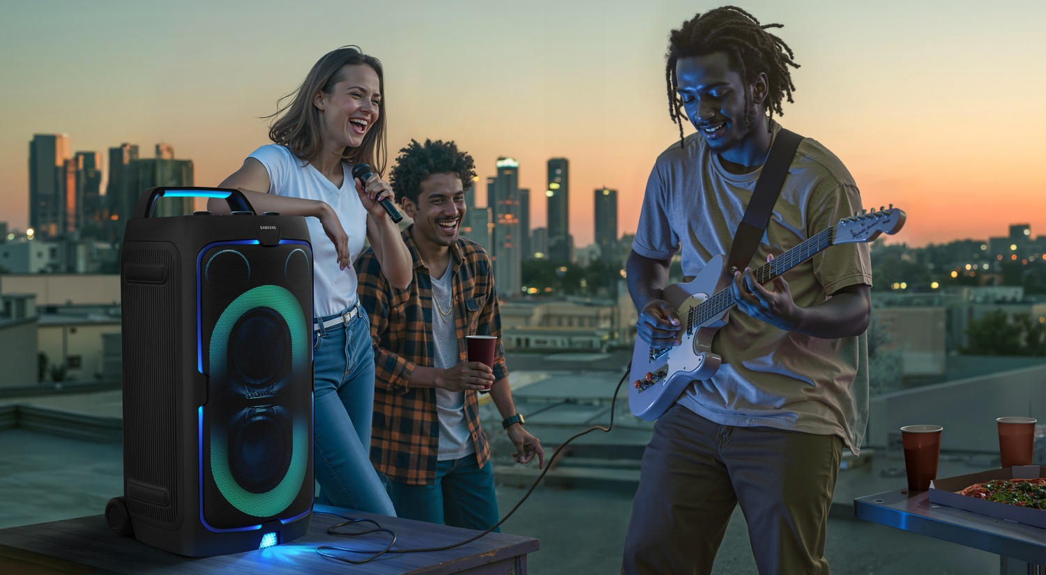 Tres amigos de fiesta en una azotea al atardecer con música y pizza.