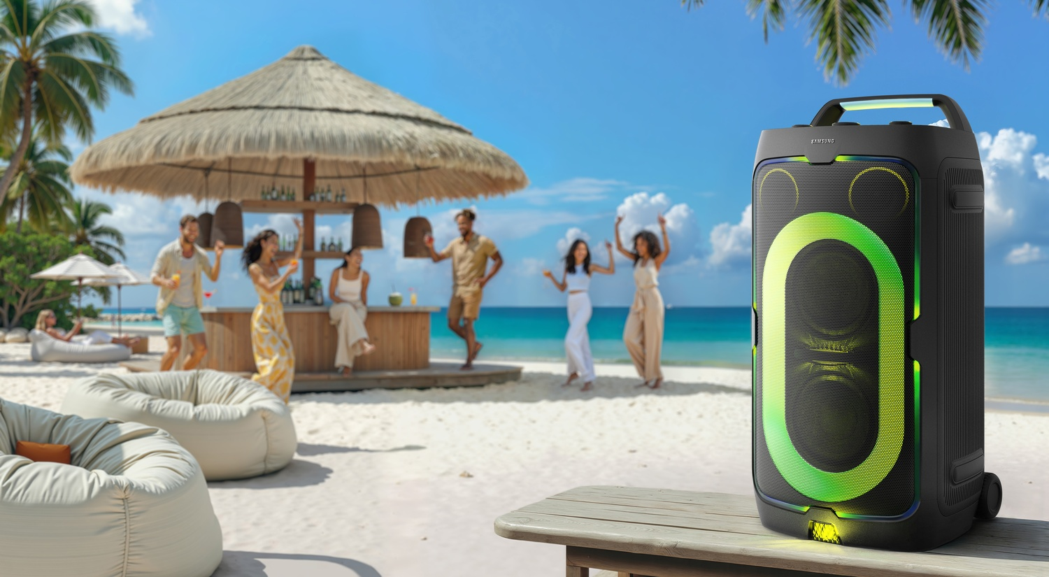 Altavoz en la playa con gente bailando y bar al fondo.