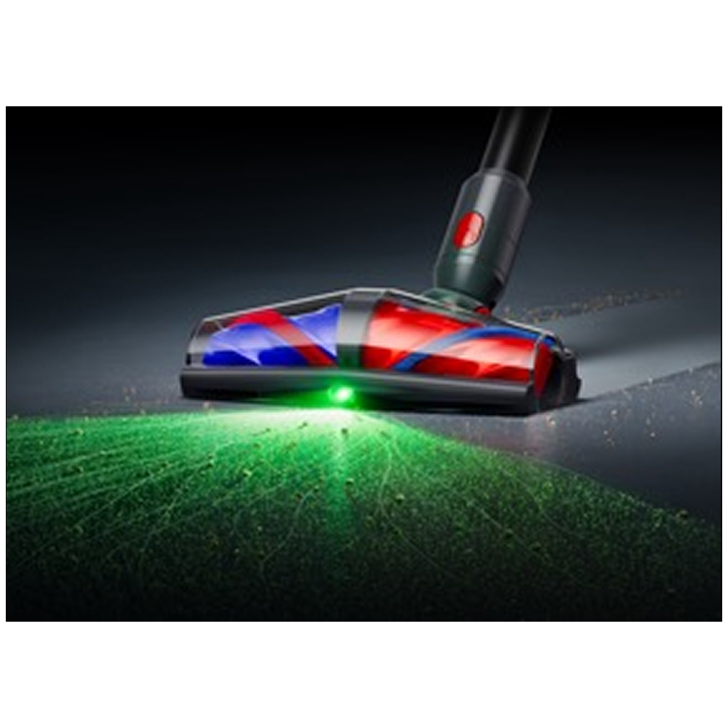 Vacuum cleaner head with green LED illuminates dust on dark floor.