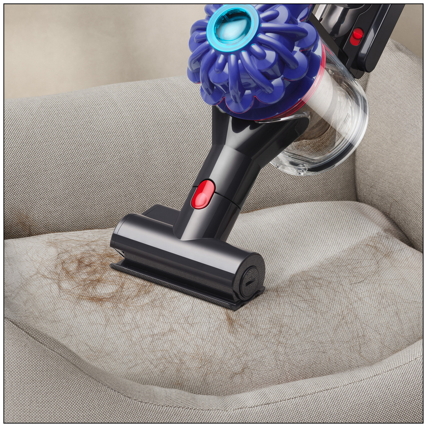 A vacuum cleaner cleans pet hair from a light gray sofa.