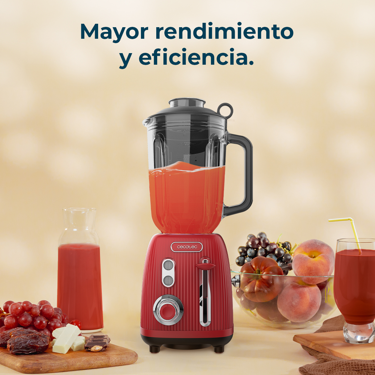 Una licuadora roja con jugo, frutas y dulces al lado.