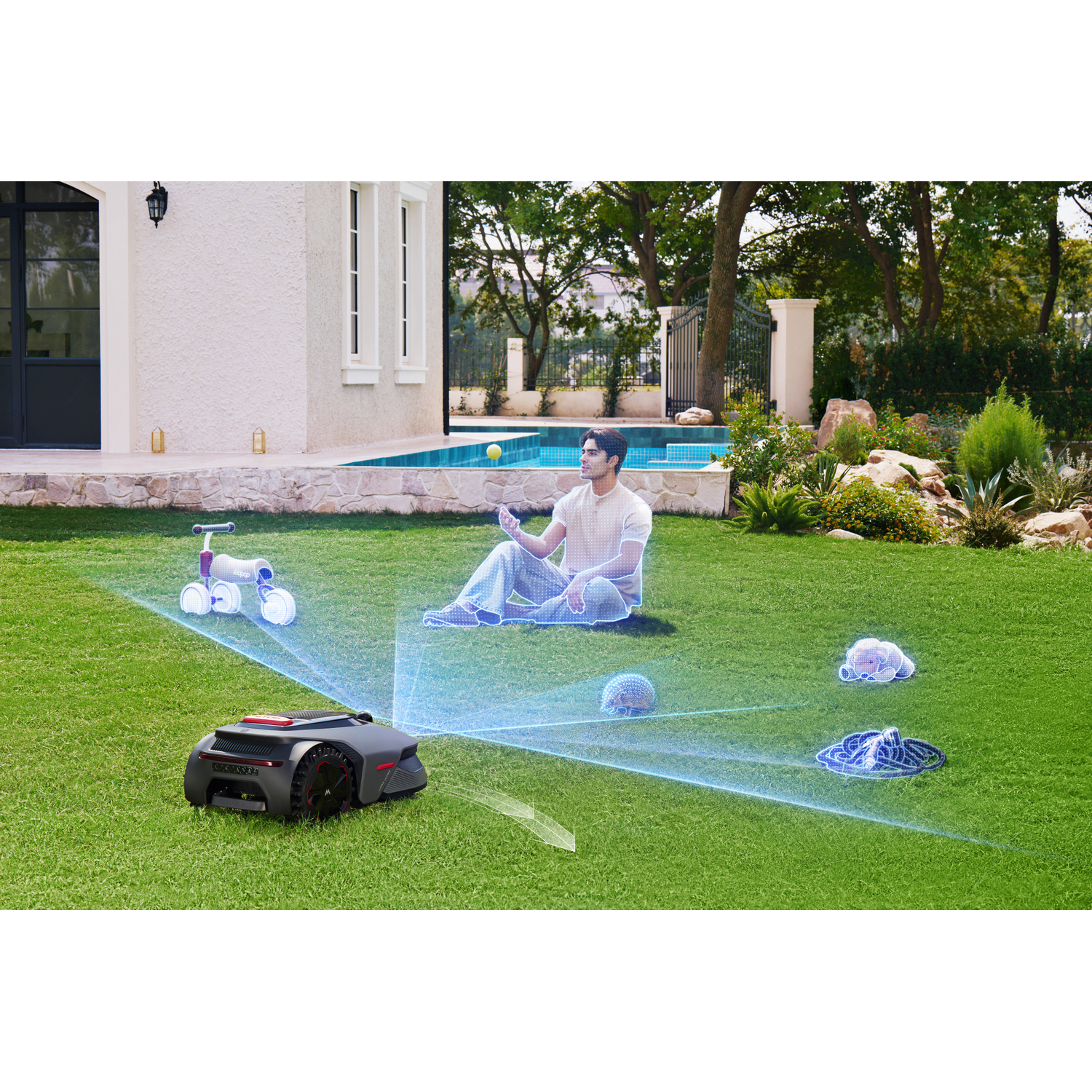 A lawn mower robot scans a man sitting on grass with a bike and toys.