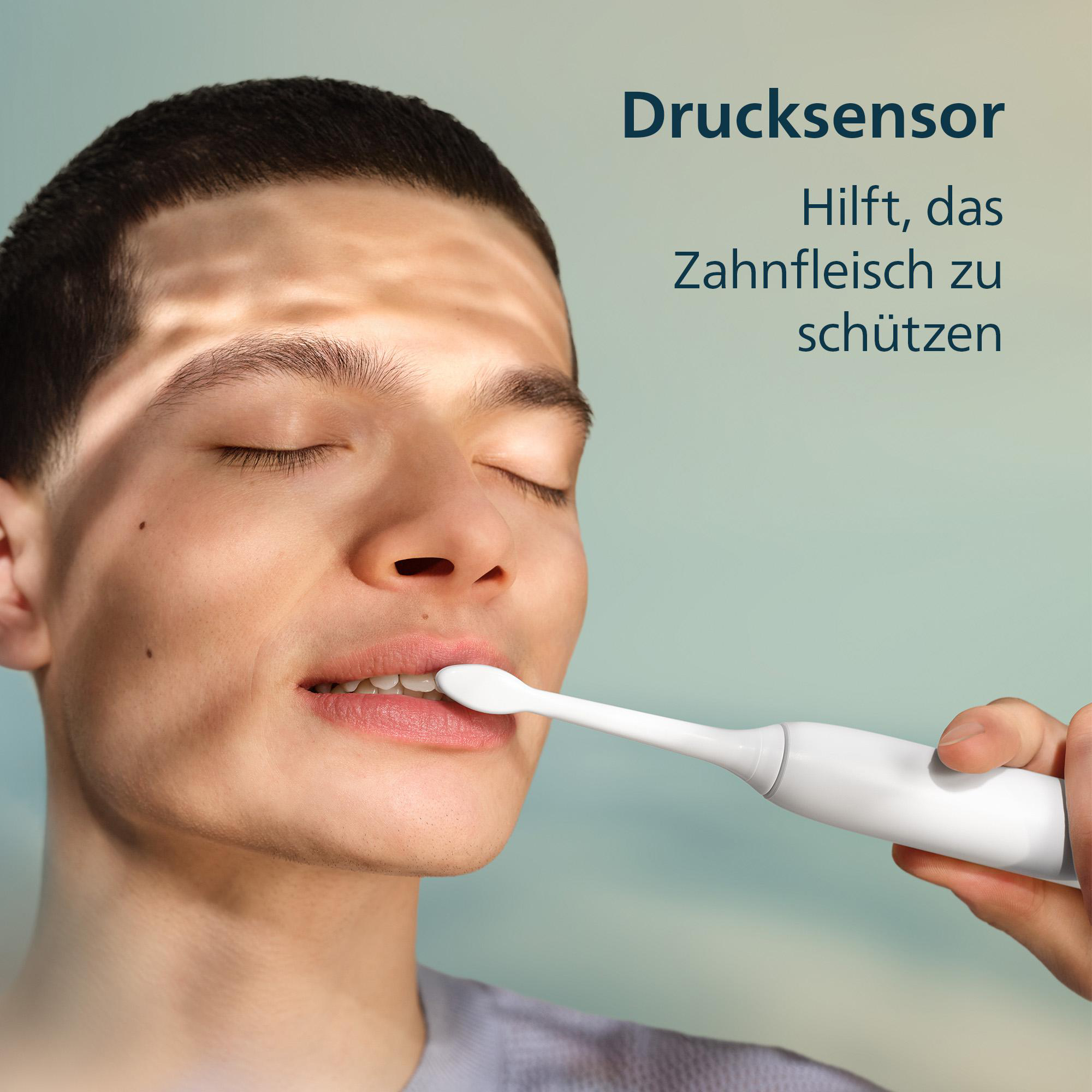 Ein Mann putzt sich die Zähne mit einer elektrischen Zahnbürste. Der Drucksensor schützt das Zahnfleisch.