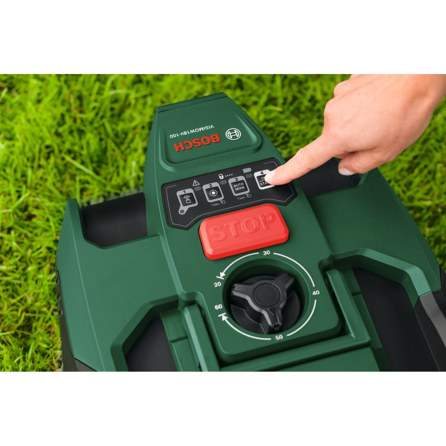 Una mano preme il pulsante di avvio di un tosaerba verde sull'erba.