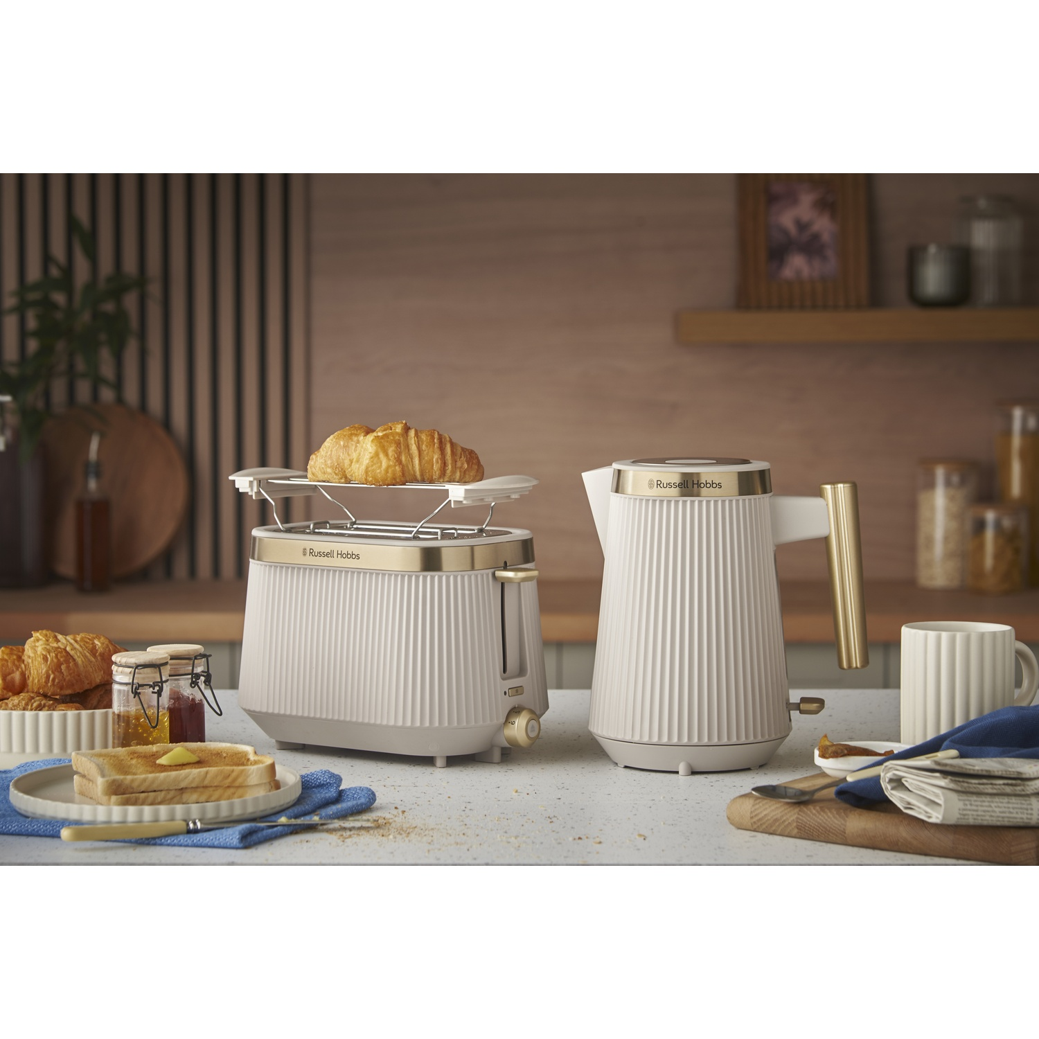 A white toaster with gold accents and a kettle beside it.