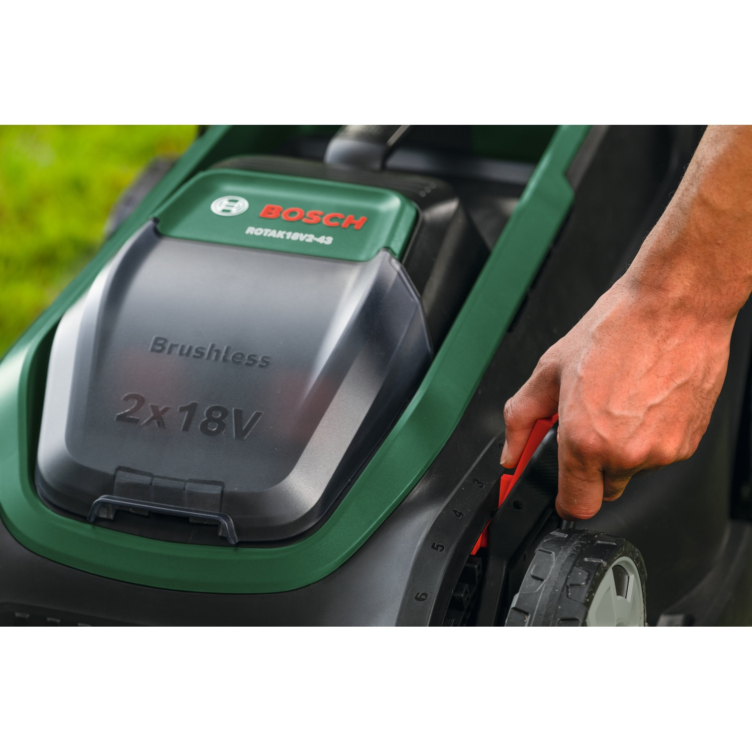 Tosaerba Bosch verde con mano che regola l'altezza di taglio.