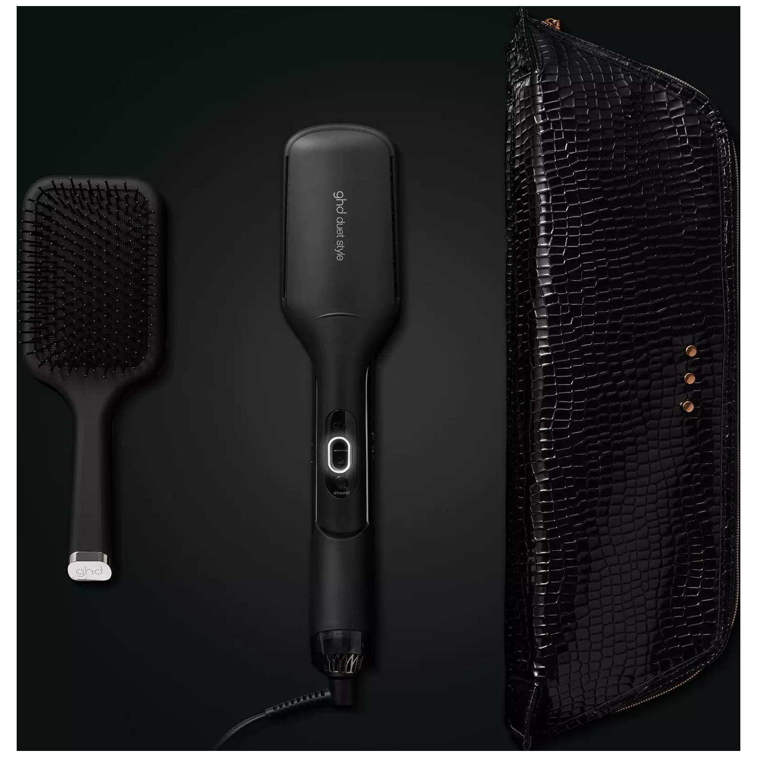 Black paddle brush, straightener, and crocodile leather case on a black background.