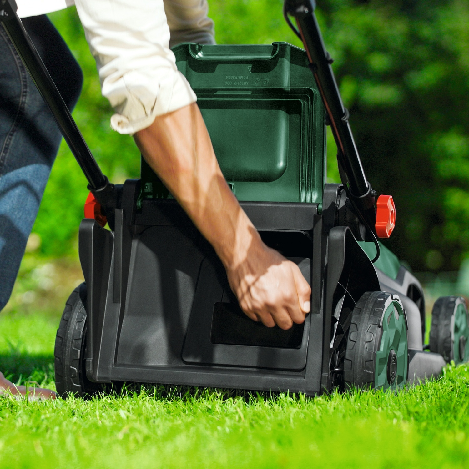 Uomo spinge tosaerba verde su erba verde.