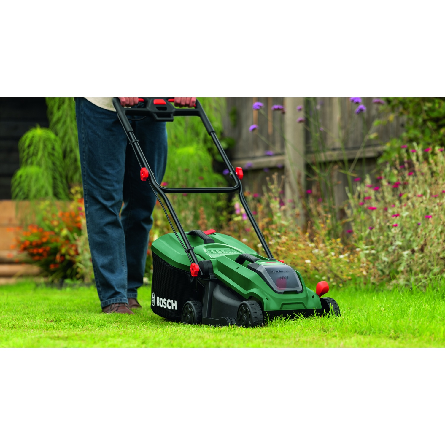 Uomo taglia il prato con rasaerba Bosch verde in giardino.