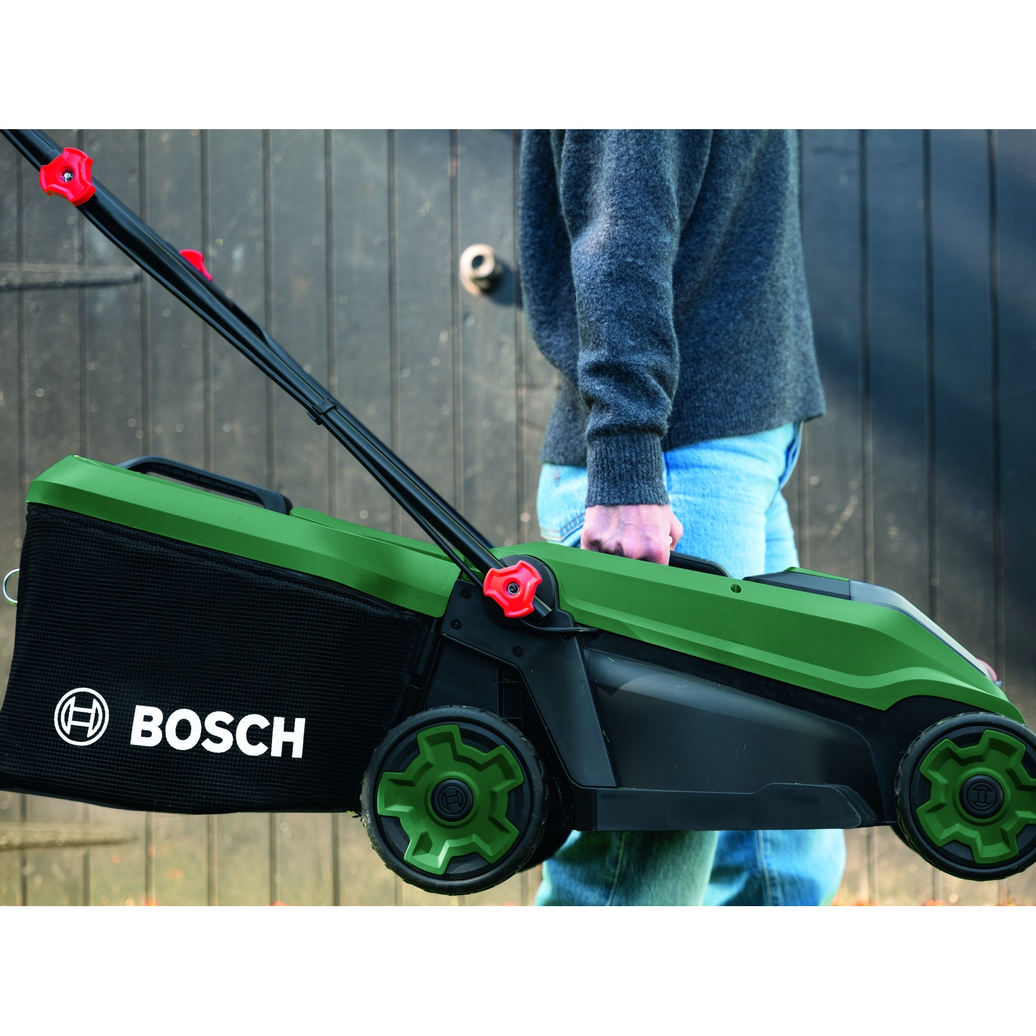 Tosaerba Bosch verde con sacco raccoglierba, tenuto da persona.
