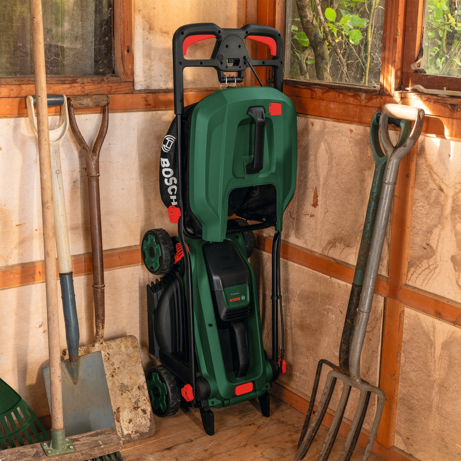 Un'idropulitrice verde si trova in un capanno con attrezzi da giardino.
