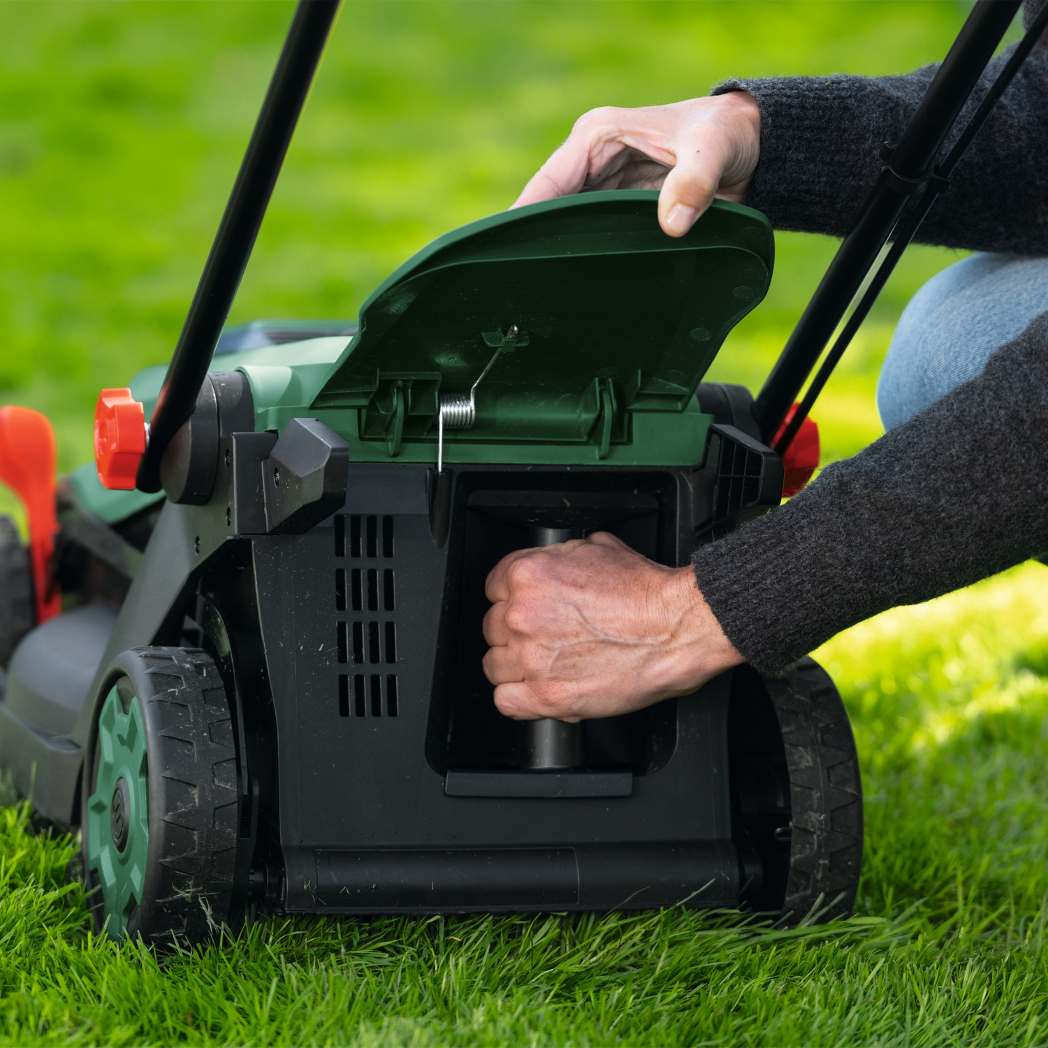 Persona apre coperchio tosaerba su erba verde.