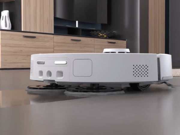 Egy fehér robotporszívó forgó kefékkel sima padlón.