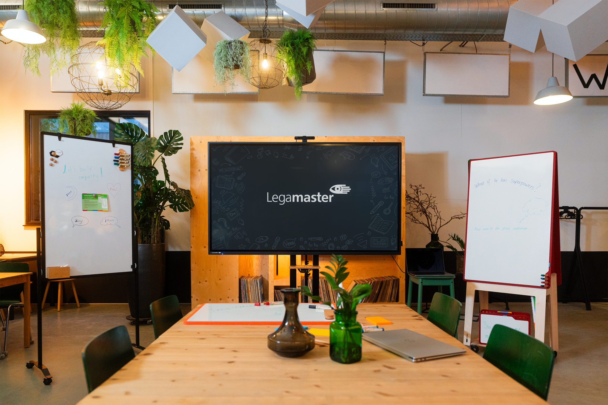 Ein Konferenzraum mit Whiteboards, einem großen Bildschirm und einem Holztisch.