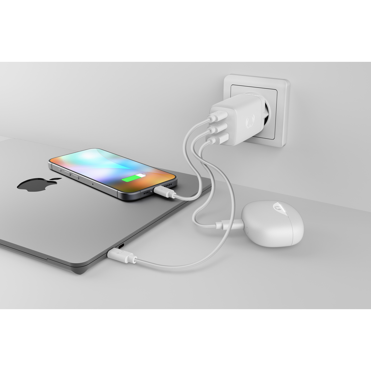 Un chargeur multiple blanc alimente un iPhone, un ordinateur portable et des écouteurs.