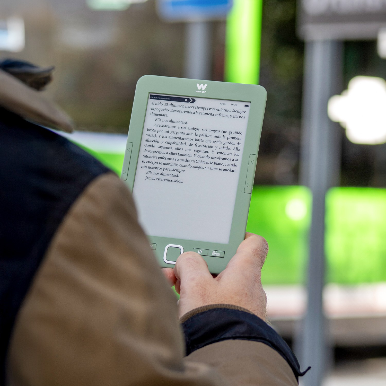 Una persona sostiene un e-reader verde claro con texto en español.