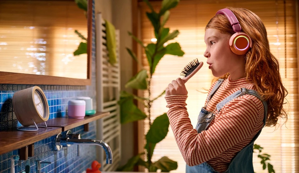 Dziewczynka w słuchawkach śpiewa do szczotki do włosów.