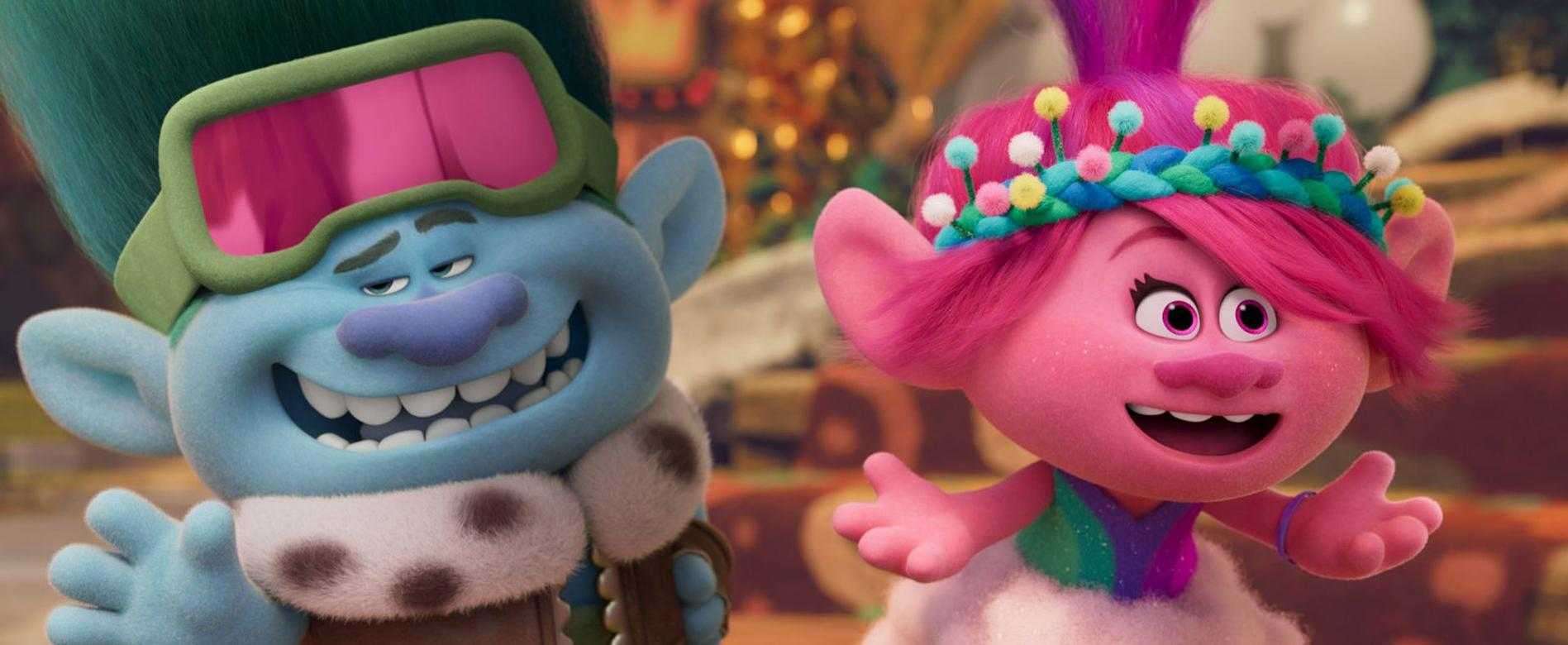 Ein blauer und ein pinker Troll lächeln vor einem verschwommenen Hintergrund.