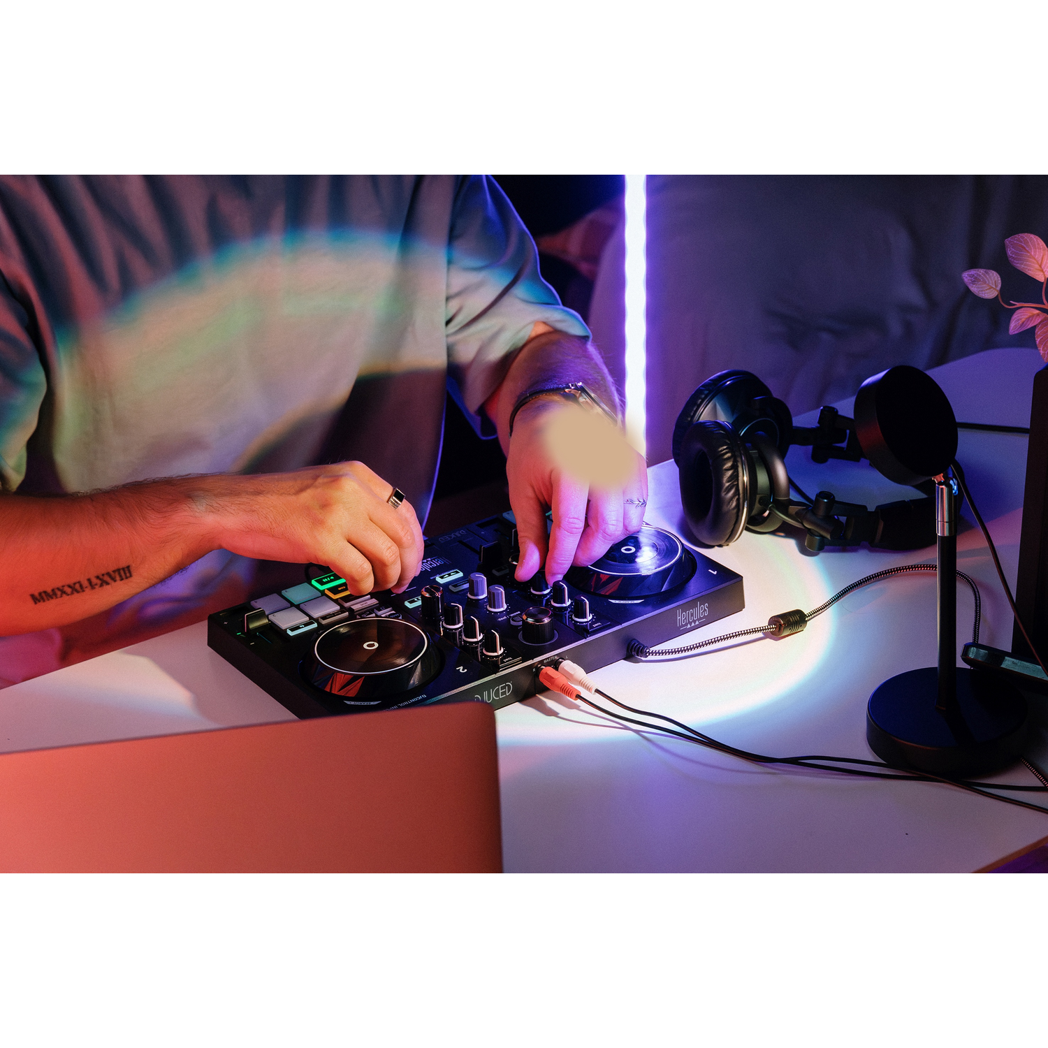 Een persoon bedient een DJ-controller met hoofdtelefoon en microfoon ernaast.