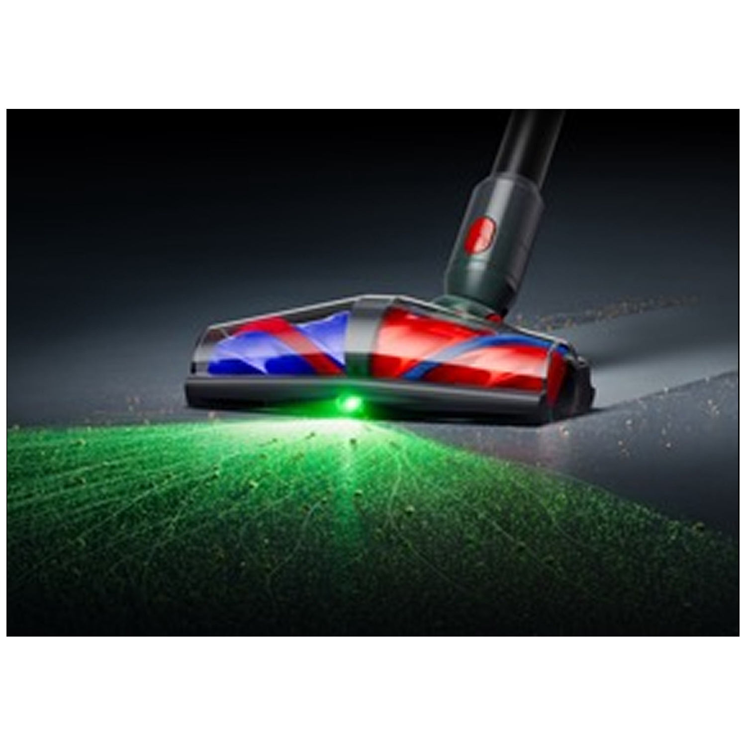 Tête d'aspirateur avec lumière verte illuminant la poussière sur sol sombre.