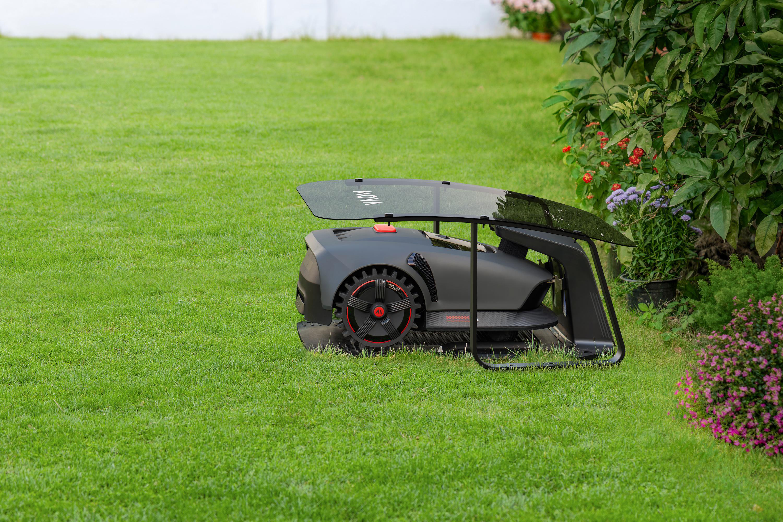 Ein dunkelgrauer Mähroboter mit roten Akzenten steht auf einem grünen Rasen.