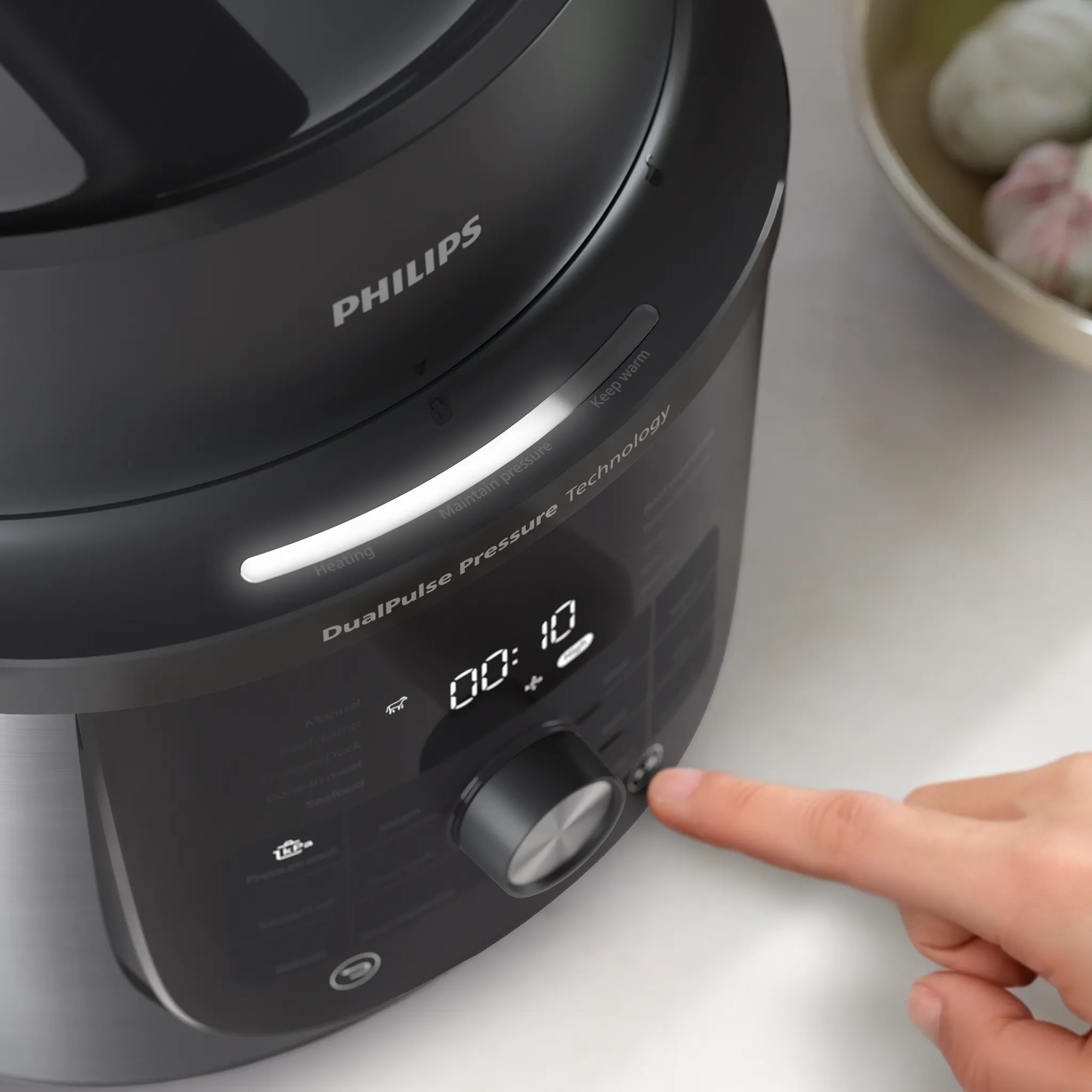 Egy ujj egy fekete Philips multifunkciós főző gombját nyomja meg.