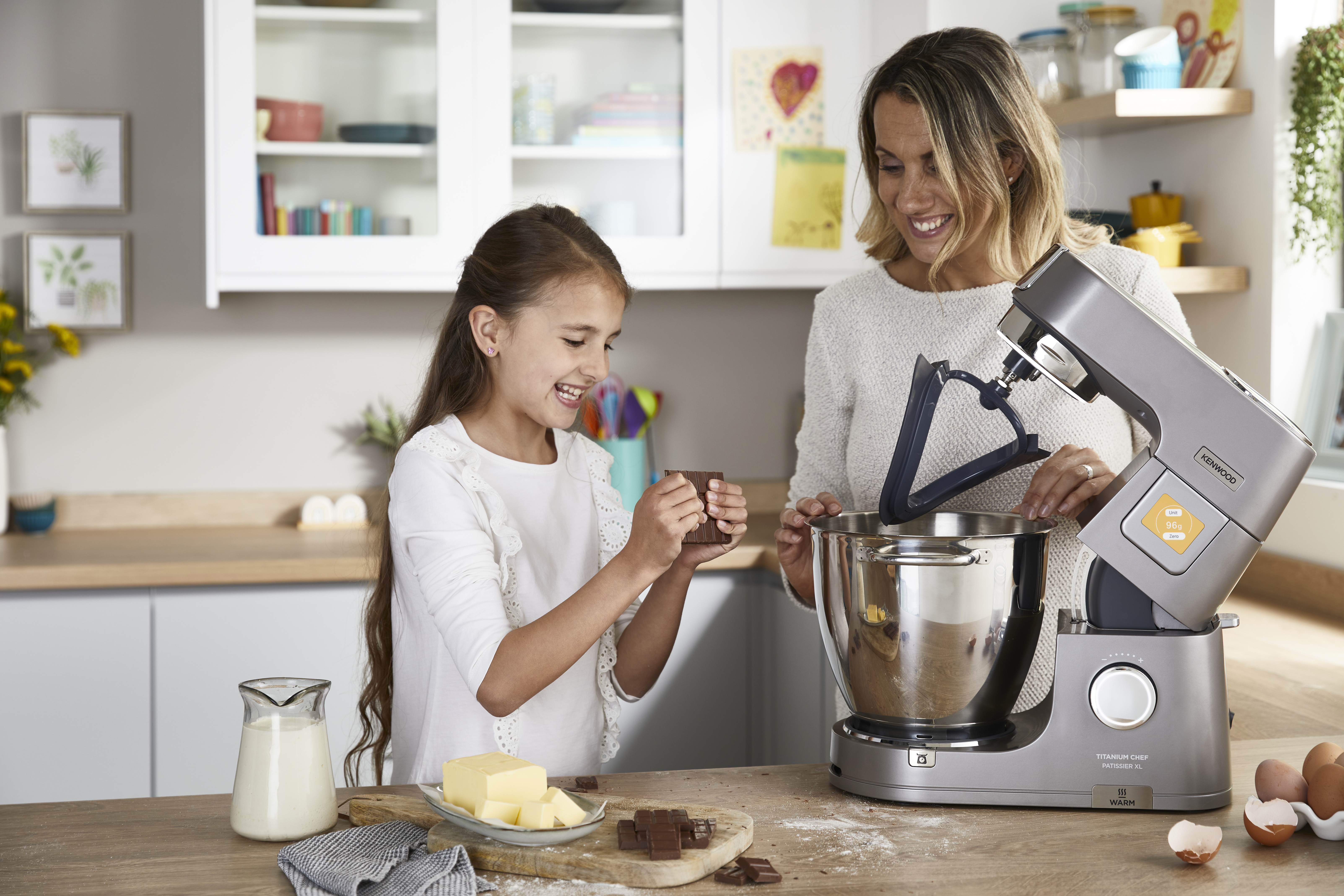 Mutter und Tochter backen zusammen in einer modernen Küche mit einer Küchenmaschine.