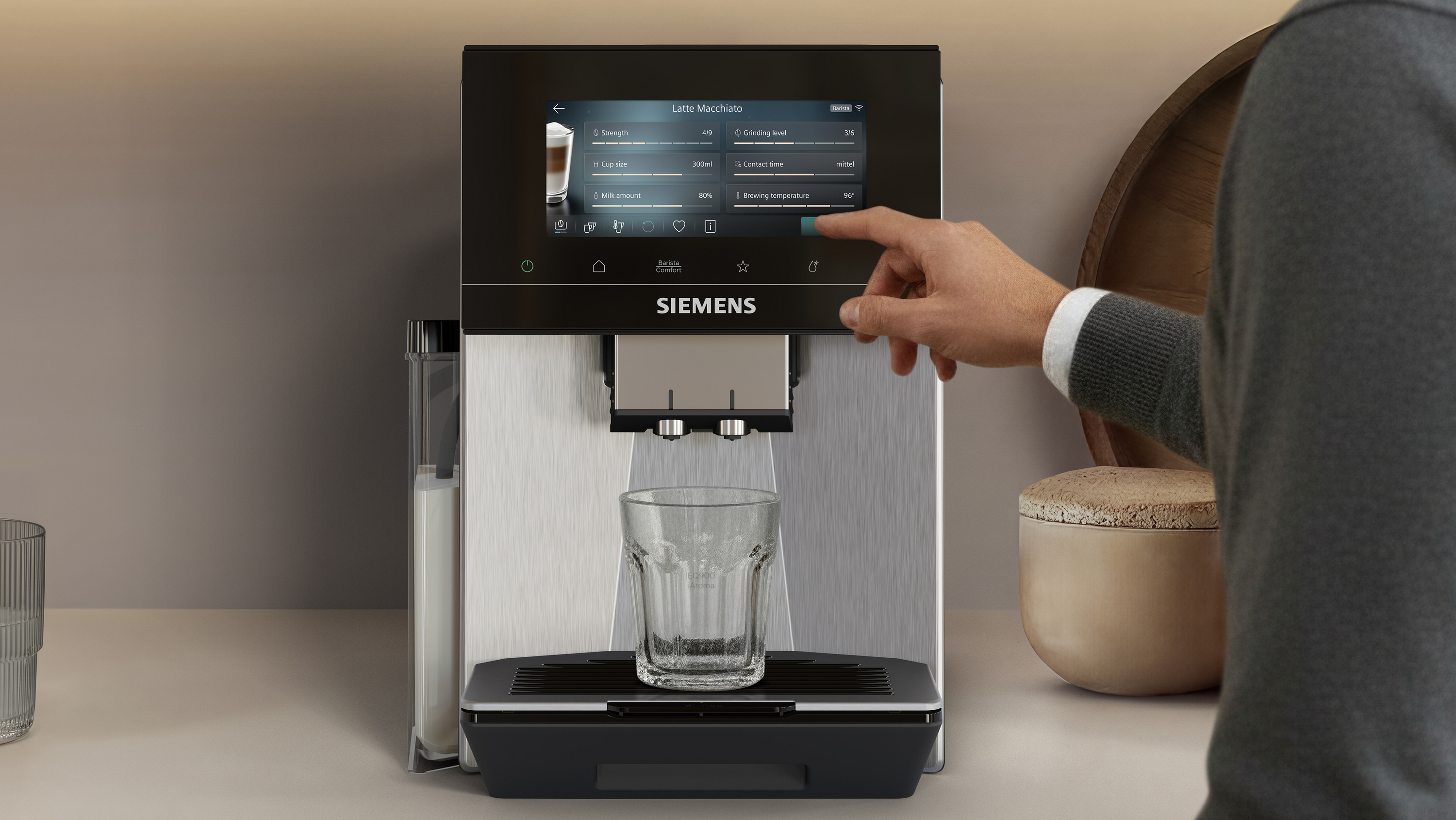 Une main utilise une machine à café Siemens préparant un Latte Macchiato.