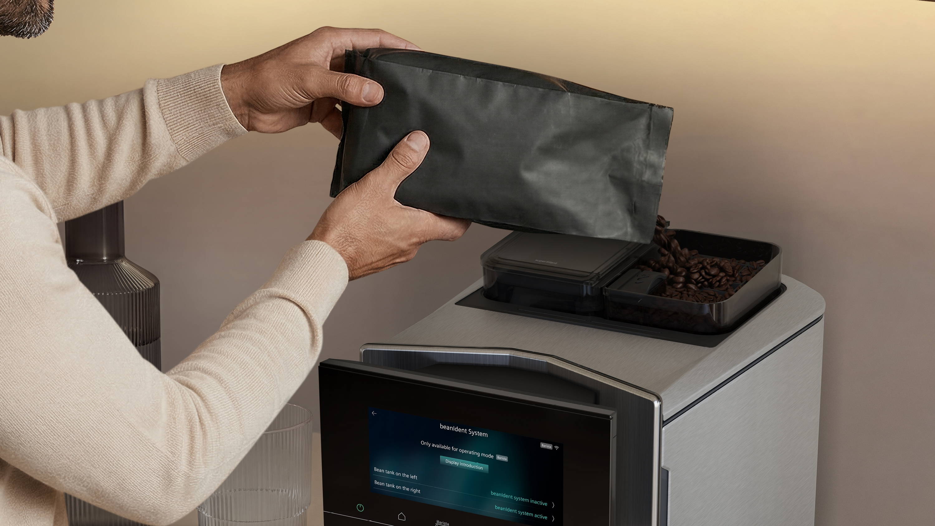 Un homme verse des grains de café d'un sac noir dans une machine à café.