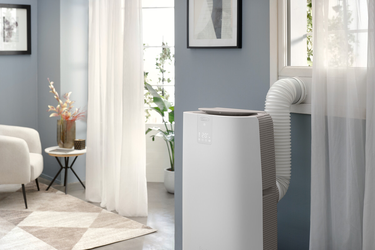 Un tuyau de climatiseur blanc mène à une fenêtre dans un salon.