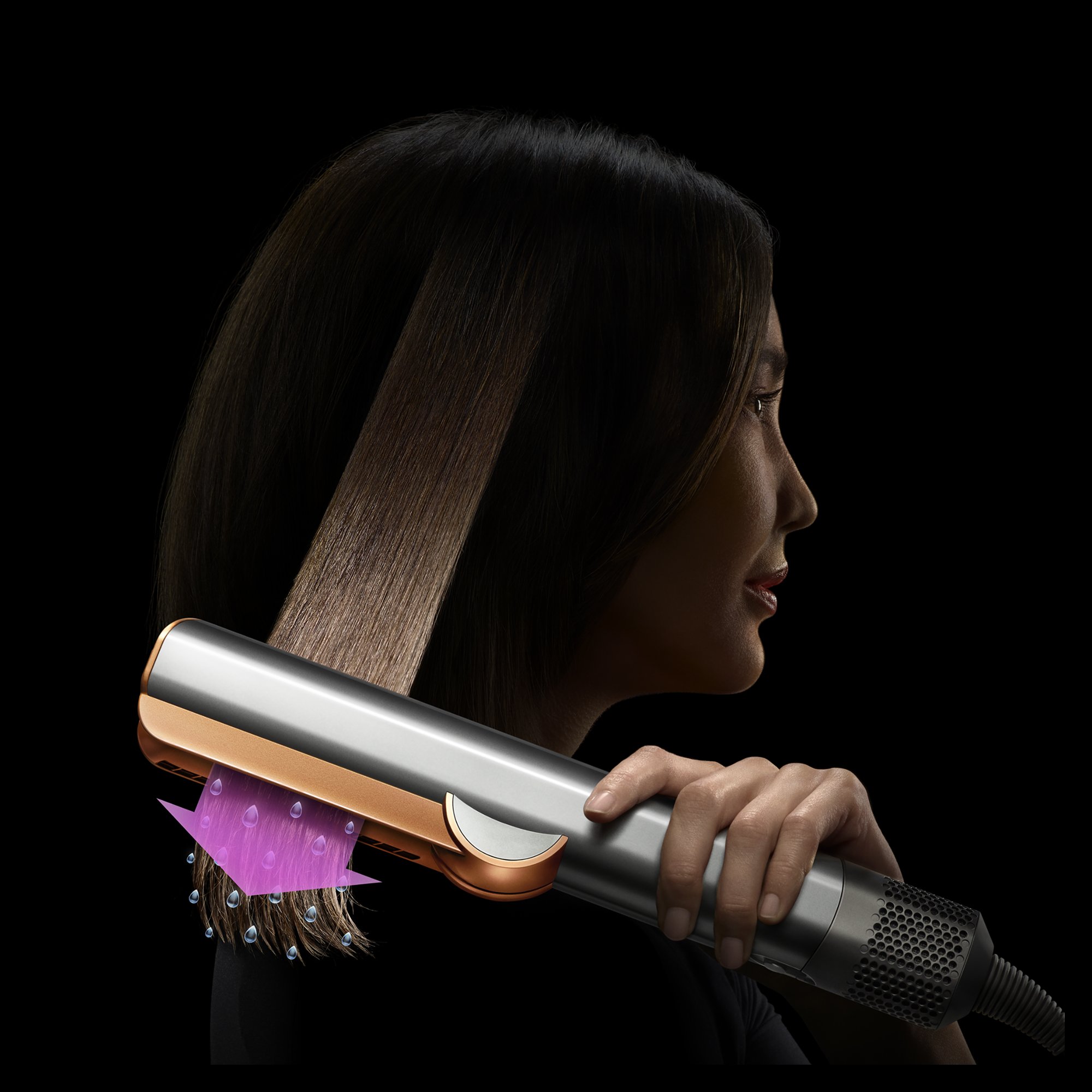 Mujer peina cabello castaño con plancha plateada y dorada que rocía vapor de agua.