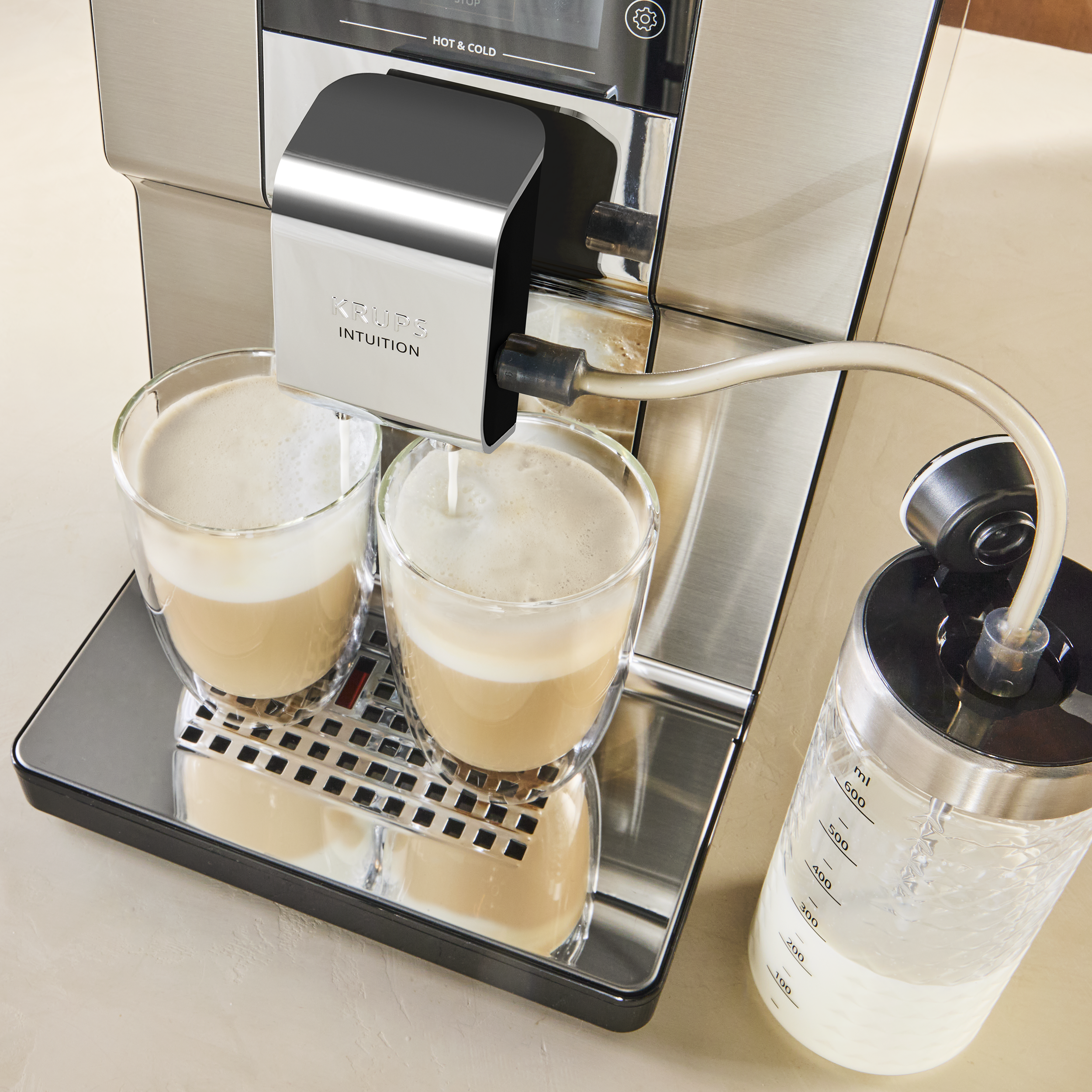 Kávéfőző két pohár cappuccinót készít tejhabosítással.