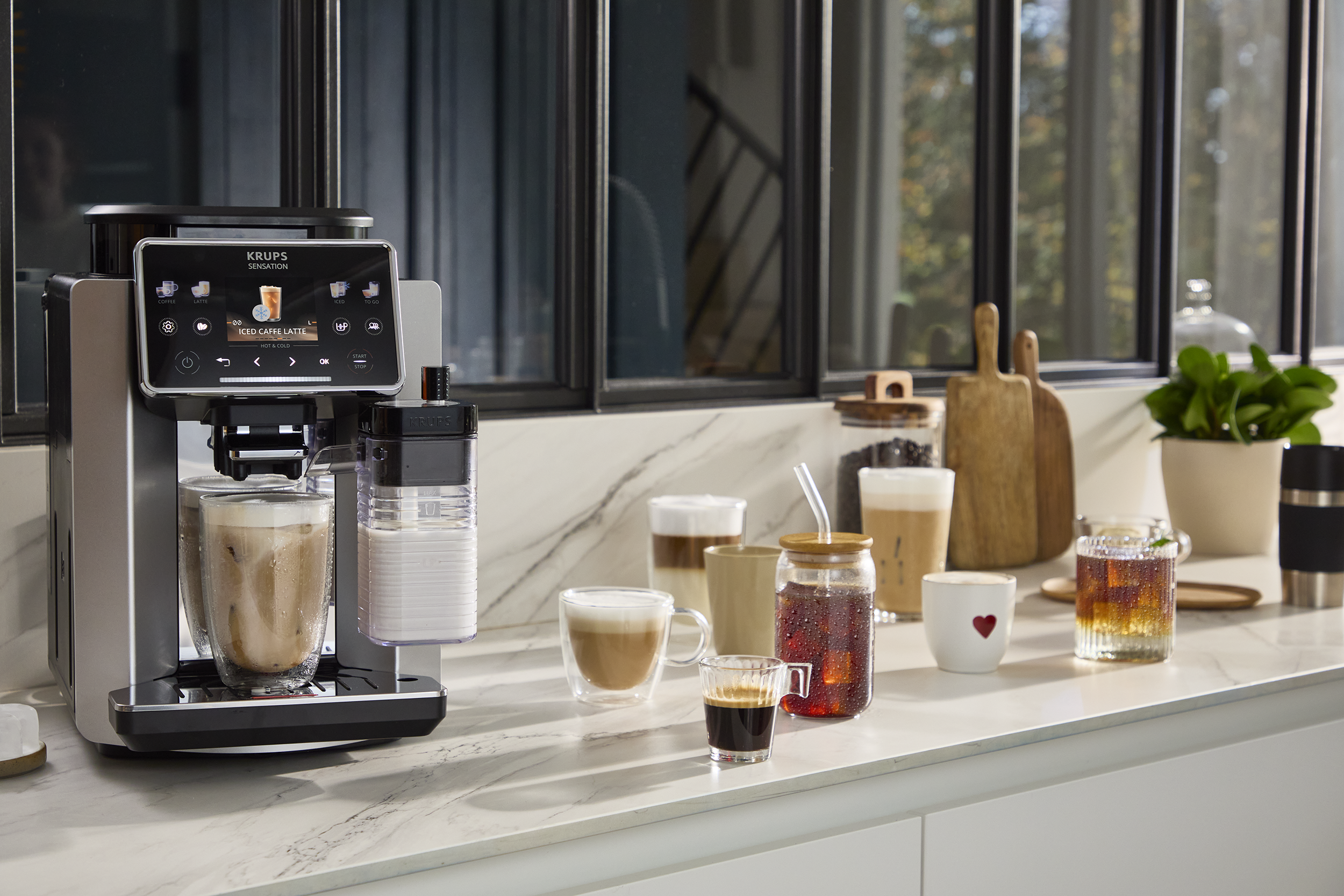 Kávéfőző jeges kávé latte-t készít egy pohárba, mellette más kávéitalok.