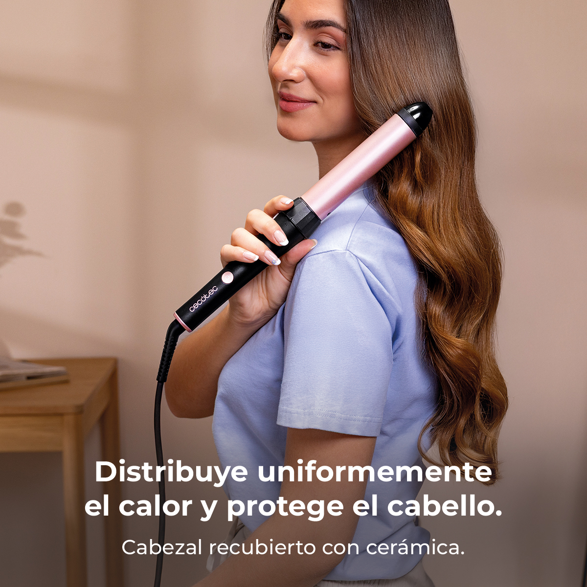 Una mujer usa un rizador rosa en su cabello castaño.