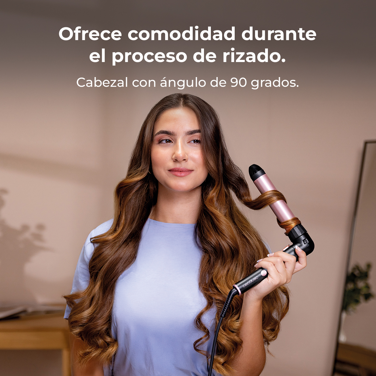 Mujer con pelo largo y castaño usa un rizador con mango en oro rosa.