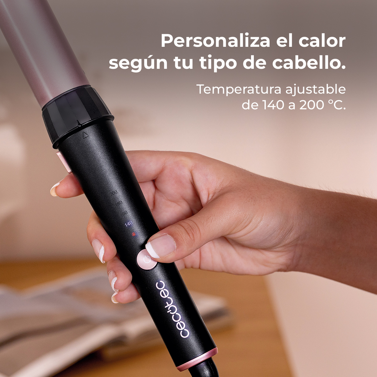 Una mano ajusta la temperatura de una plancha de pelo negra con detalles rosas.