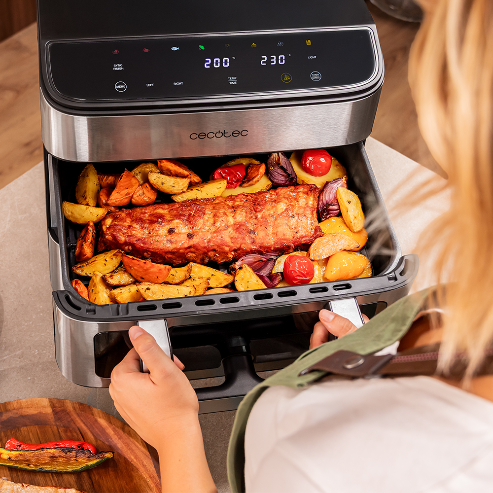 Freidora de aire con costillas, patatas, cebollas y tomates.