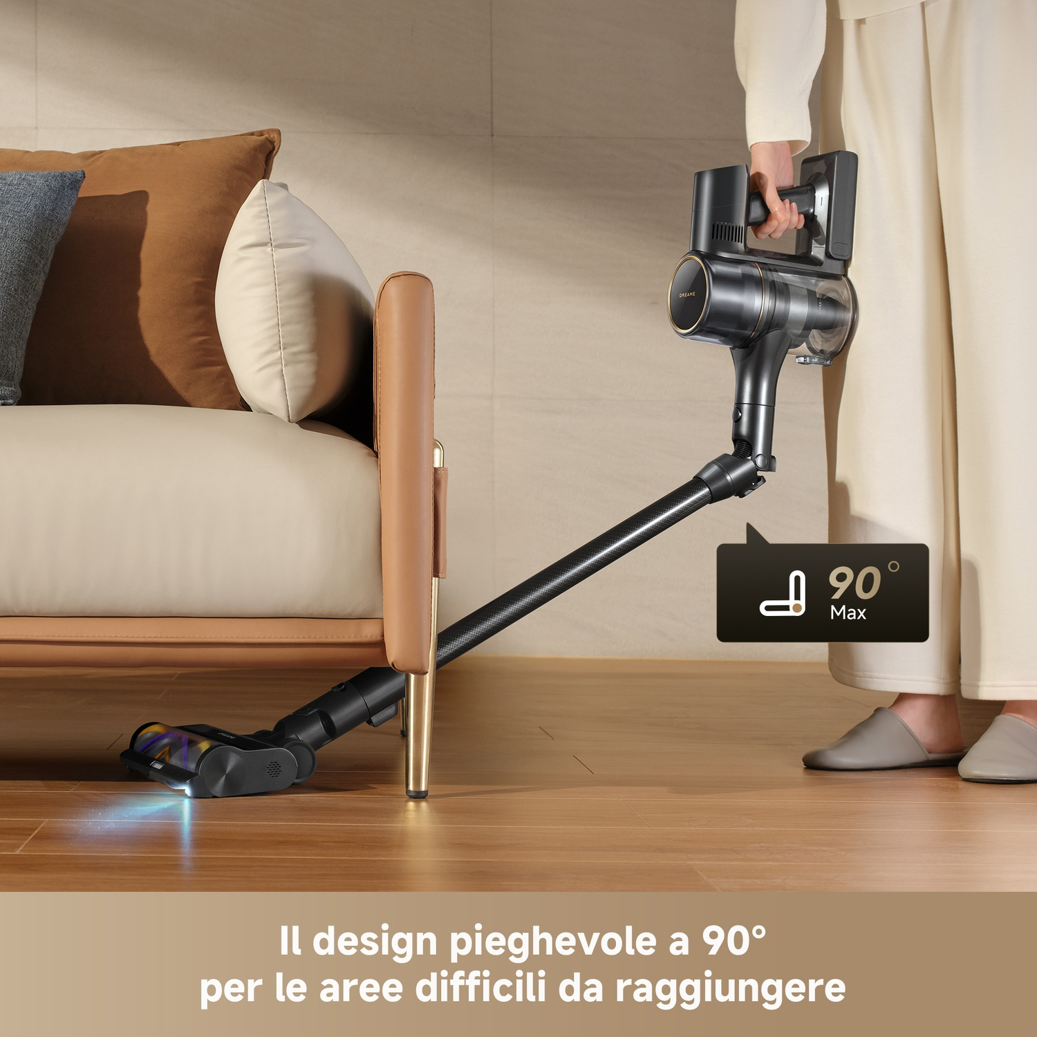 Un aspirapolvere senza fili con tubo pieghevole pulisce sotto un divano.