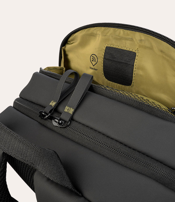 Primer plano de una mochila negra con compartimento abierto mostrando un logo de rastreador.