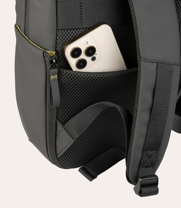 Un teléfono inteligente de color claro está en un bolsillo exterior de malla de una mochila gris.