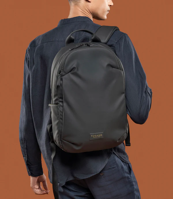 Un hombre lleva una mochila negra. Fondo marrón.