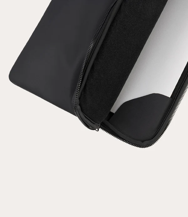 Funda negra para portátil, parcialmente abierta, mostrando un dispositivo blanco.