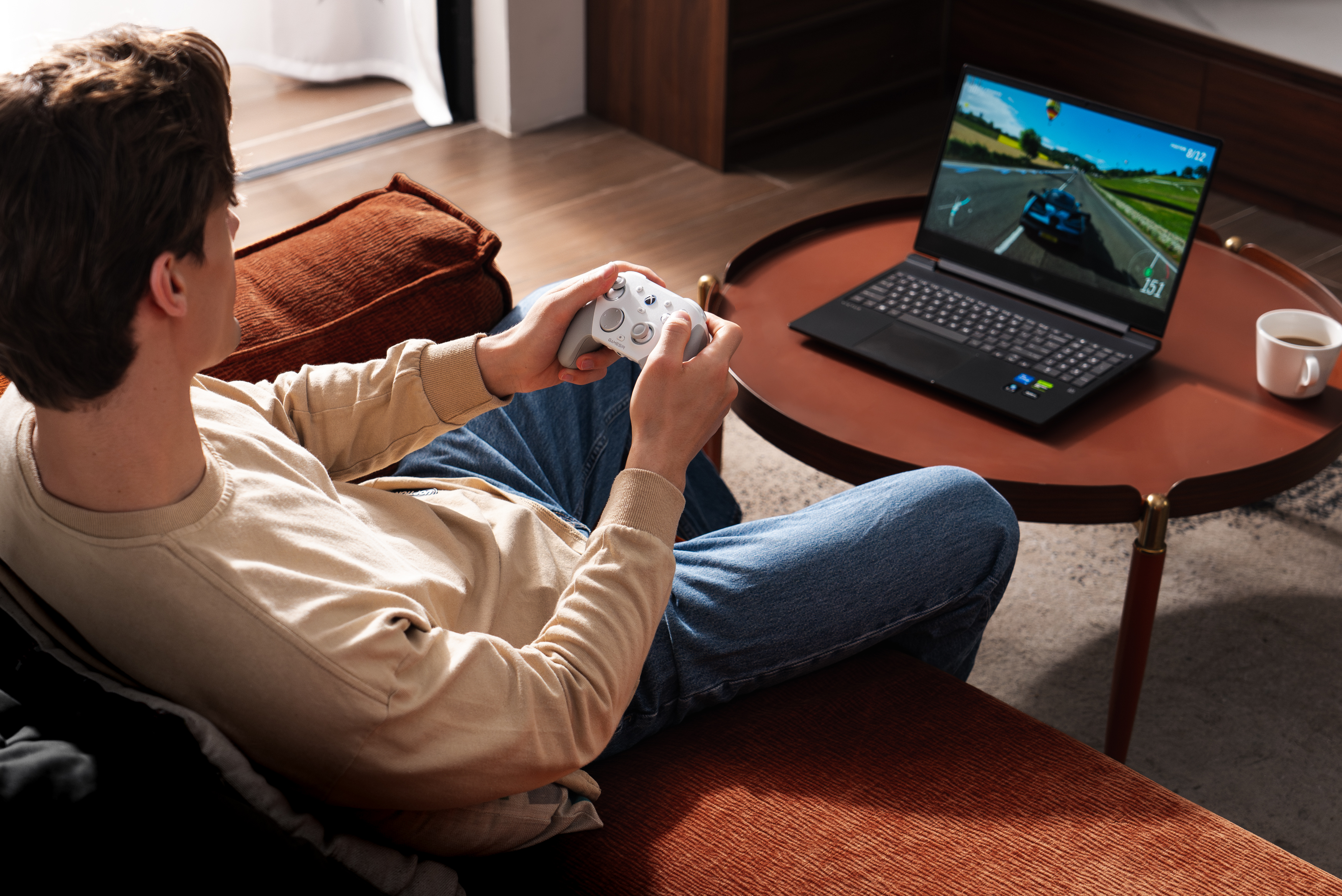 Un uomo gioca a un gioco di corse su un laptop con un controller.